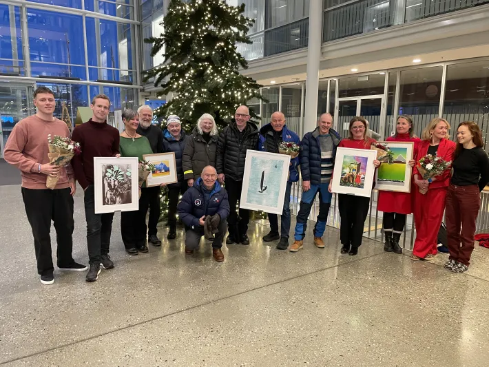 Alle som mottok Troms&oslash; kommunes priser i 2024 st&aring;r foran juletreet inne p&aring; r&aring;dhuset og smiler.
