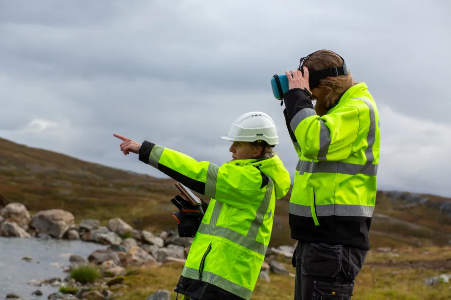 To arbeidere st&aring;r ved drikkevannskilde.