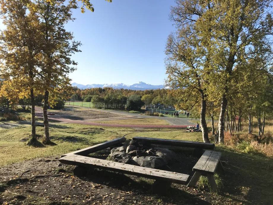 B&aring;lplass med benker p&aring; en liten h&oslash;yde med Charlottenlund aktivitets- og friluftspark i bakgrunn.