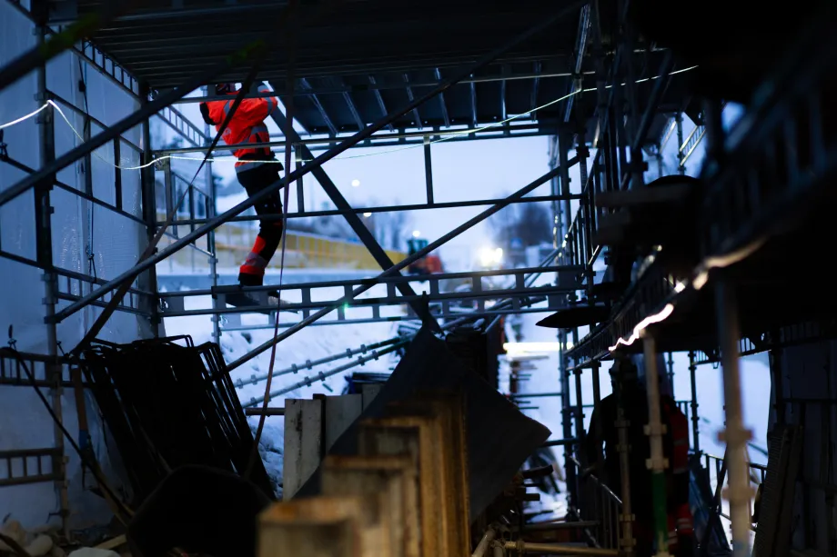 Viser arbeidere som bygger stillas inni telt langs Gyllenborgbrua