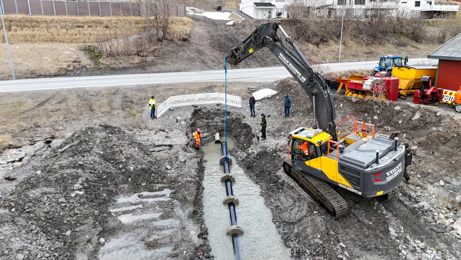 Sjøledning løftes på plass i grøft med gravemaskin