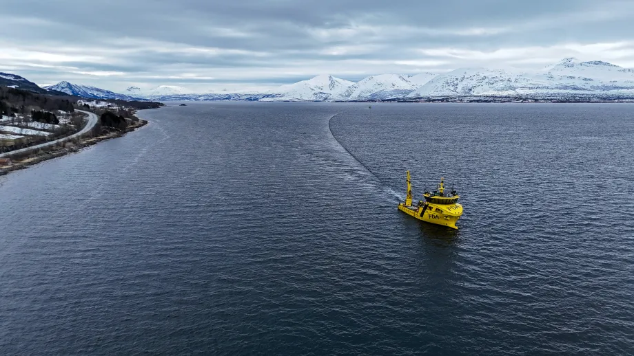 Båt sleper sjøledning på havoverflaten