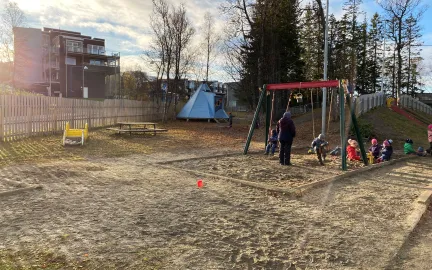 Workinnmarka barnehage uteomr&aring;de med lavvo, husker og mange barn en solrik sommerdag