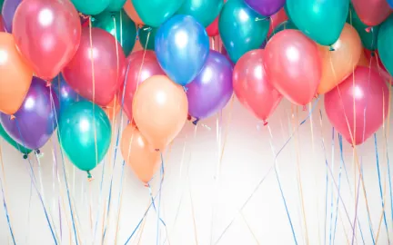R&oslash;de, gr&oslash;nne, lilla og oransje ballonger mot hvit bakgrunn. Illustrasjonsfoto.
