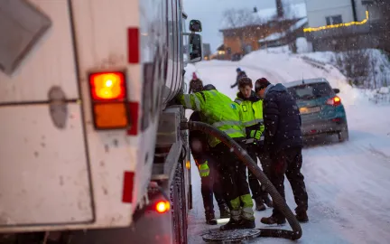 Fire arbeidere st&aring;r over &aring;pen kum midt i gate i Troms&oslash;.