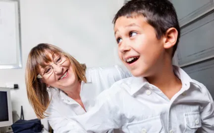 Kvinnelig helsesykepleier sammen med et barn p&aring; et unders&oslash;kelsesrom. Begge smiler til hverandre.