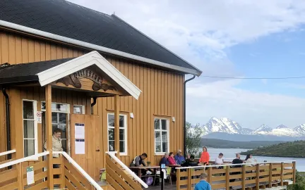 Bilde som viser bygningen Bryggeloftet p&aring; Hella med fjell og hav i bakgrunnen