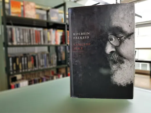 Ei bok med svart bakgrunn, hvit og r&oslash;d skrift og et portrett av en eldre mann i sort-hvitt. Boka er "Samlede dikt" av Kolbein Falkeid. Foto.