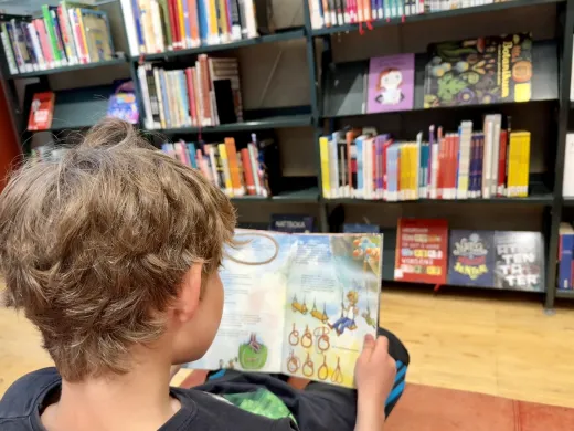 Barn leser bok på bibliotek Barn leser bok på bibliotek
