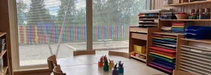 Inneomr&aring;de i Sj&oslash;mannsbyen barnehage med formingsrom, sitteomr&aring;de med fargestifter og hyller med farget papir.