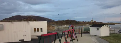 Sommar&oslash;y barnehage uteomr&aring;de med husker og sandkasse en sommerdag