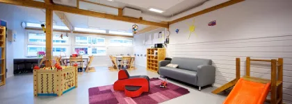 Iinneomr&aring;de med sofa, bord, lekekasser og sklie i Prestvannet studentbarnehage