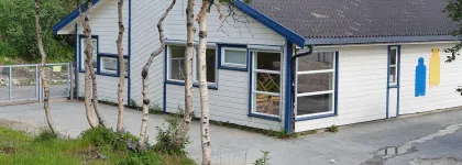 Soldagen barnehage sett utenfra med skog og gr&oslash;nt gress en sommerdag